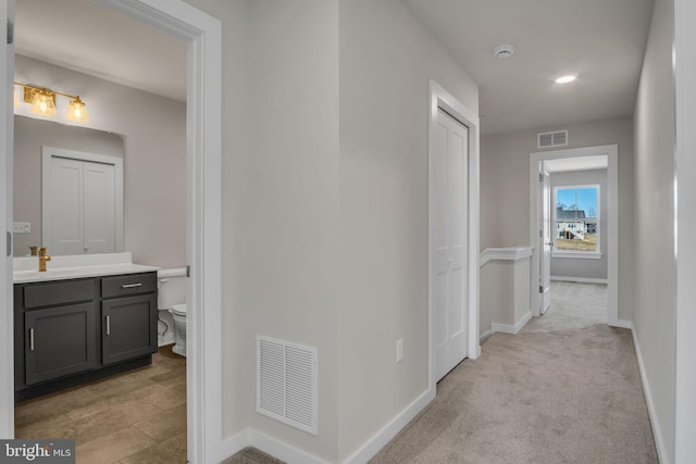 corridor featuring carpet, baseboards, and visible vents