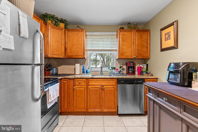 kitchen with stainless steel appliances, light stone countertops, sink, and light tile patterned floors