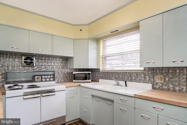 kitchen with crown molding, backsplash, white appliances, and wooden counters