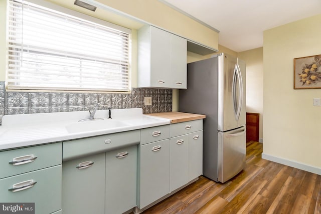 kitchen featuring dark hardwood / wood-style floors, stainless steel fridge, sink, and backsplash