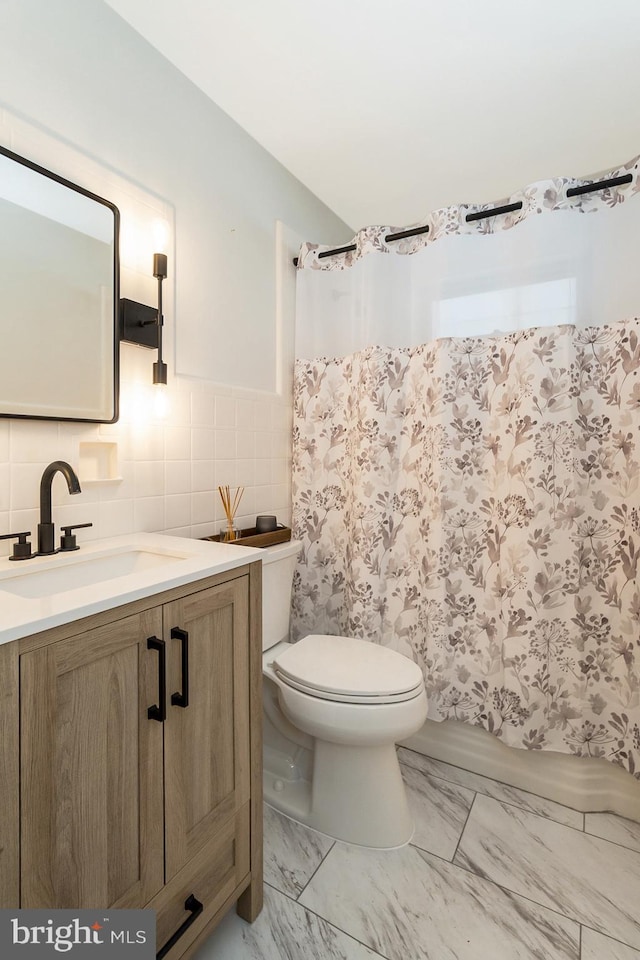 bathroom with vanity, tile walls, and toilet