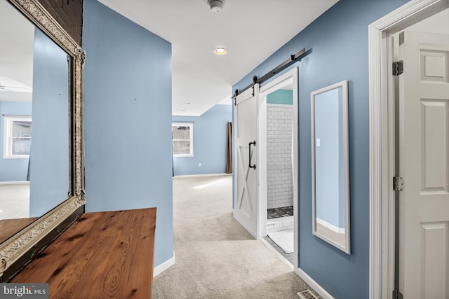 corridor featuring a barn door and carpet