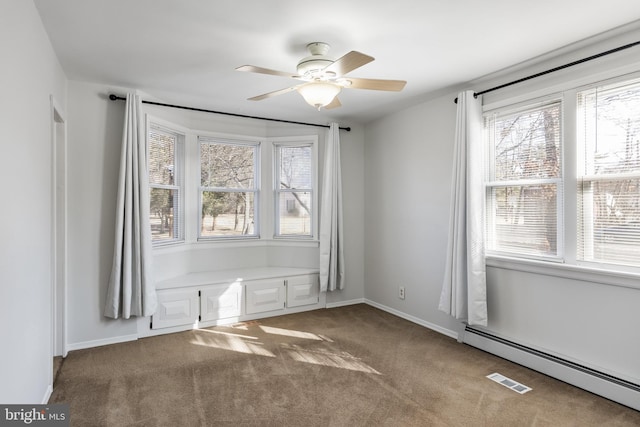 carpeted empty room featuring ceiling fan and a baseboard radiator