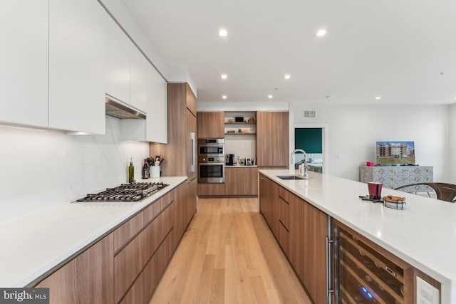 kitchen with wine cooler, sink, white cabinetry, light hardwood / wood-style flooring, and stainless steel appliances