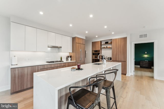 kitchen featuring white cabinetry, appliances with stainless steel finishes, a kitchen bar, and a spacious island