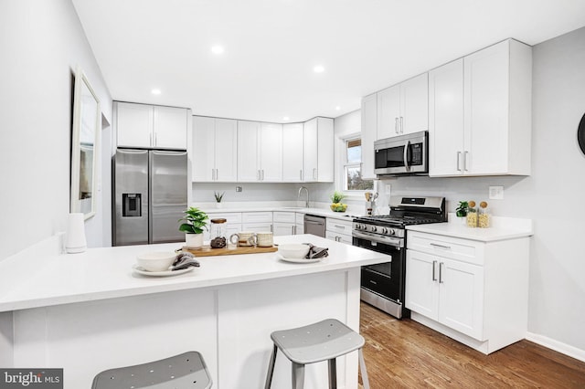 kitchen featuring stainless steel appliances, white cabinetry, sink, and a breakfast bar area