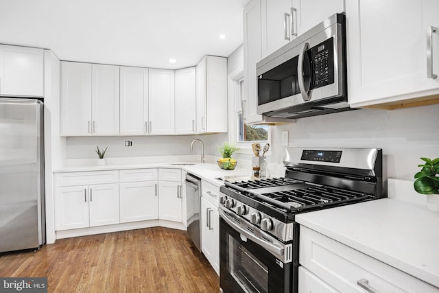 kitchen with white cabinetry, sink, stainless steel appliances, and light wood-type flooring