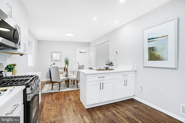 kitchen featuring kitchen peninsula, dark hardwood / wood-style floors, white cabinets, and appliances with stainless steel finishes