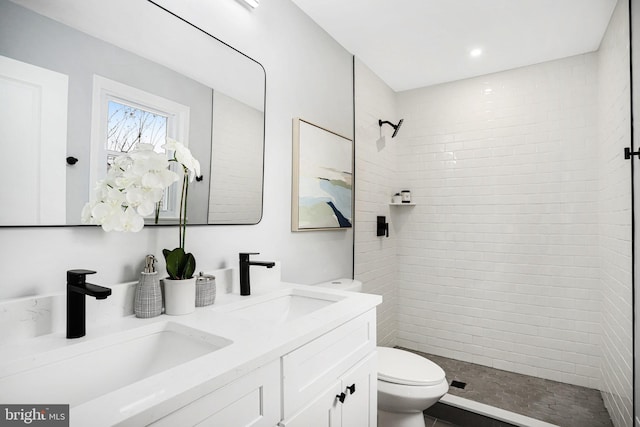 bathroom featuring vanity, tiled shower, and toilet