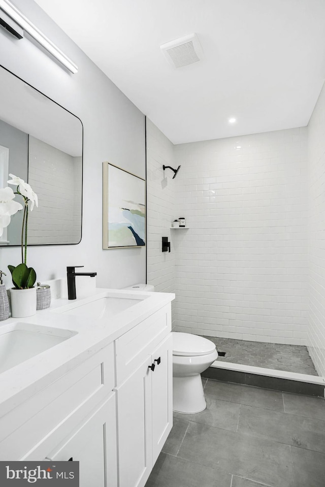 bathroom featuring tiled shower, vanity, and toilet