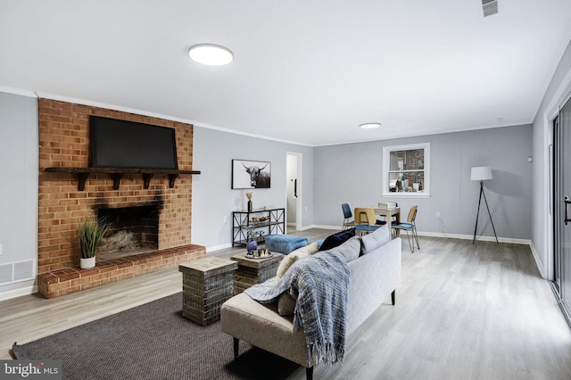 living room featuring a brick fireplace, crown molding, and wood-type flooring