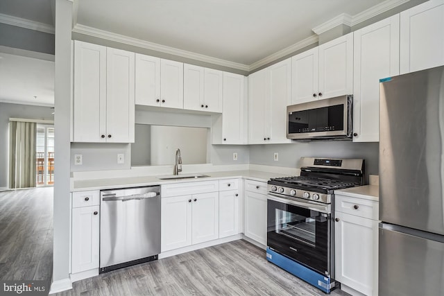 kitchen featuring sink, white cabinetry, light wood-type flooring, ornamental molding, and stainless steel appliances