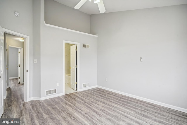 unfurnished bedroom featuring ceiling fan, ensuite bathroom, and light hardwood / wood-style floors