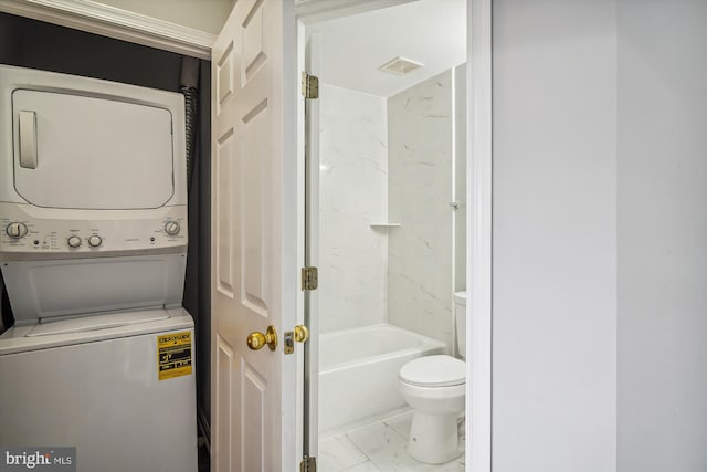 bathroom featuring toilet, tiled shower / bath, and stacked washing maching and dryer