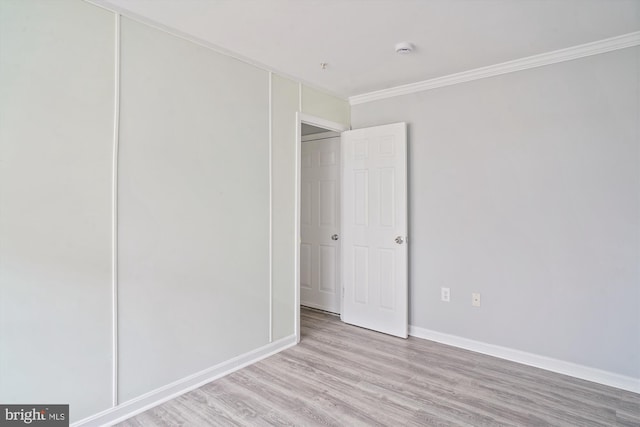 unfurnished bedroom featuring light hardwood / wood-style flooring, ornamental molding, and a closet