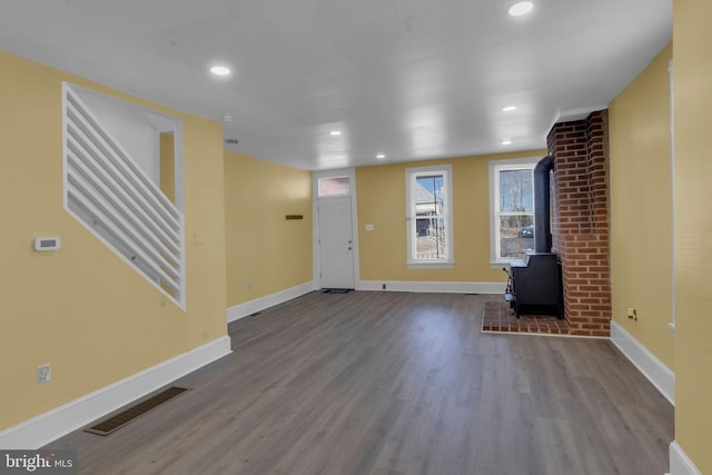 unfurnished living room featuring hardwood / wood-style flooring and a wood stove