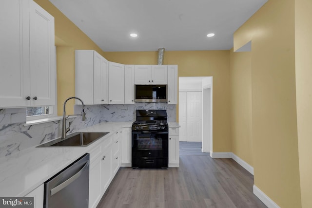 kitchen featuring appliances with stainless steel finishes, tasteful backsplash, white cabinetry, sink, and light stone countertops