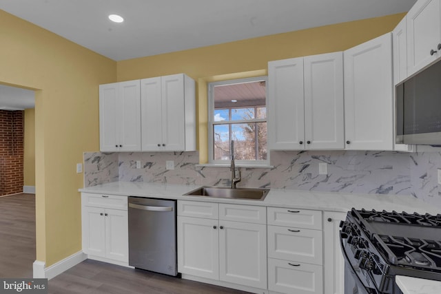 kitchen with tasteful backsplash, wood-type flooring, sink, white cabinets, and stainless steel appliances