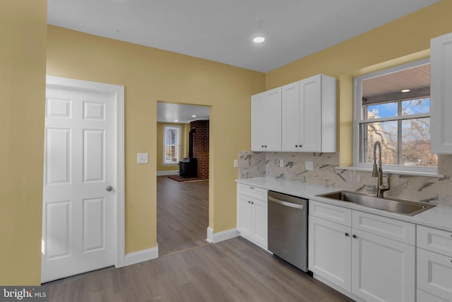 kitchen with sink, decorative backsplash, stainless steel dishwasher, and white cabinets