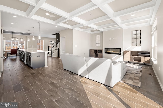 living room with coffered ceiling, beam ceiling, and sink