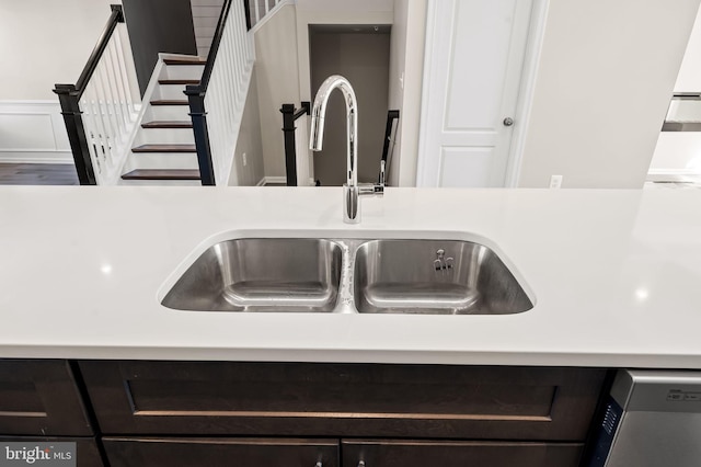 interior details with stainless steel dishwasher, sink, and dark brown cabinets