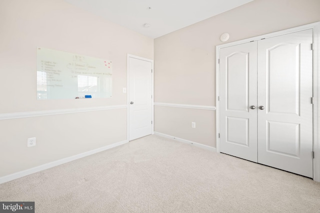 unfurnished bedroom featuring light colored carpet and a closet