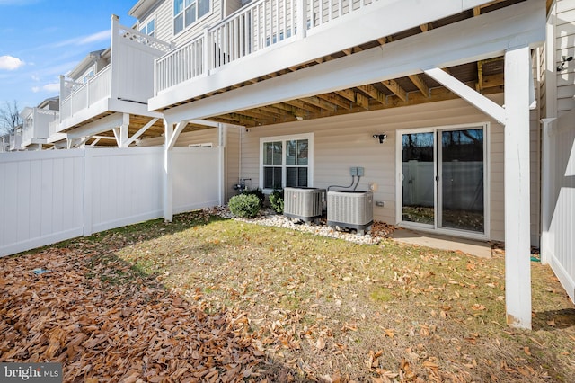 back of house featuring a lawn and central air condition unit