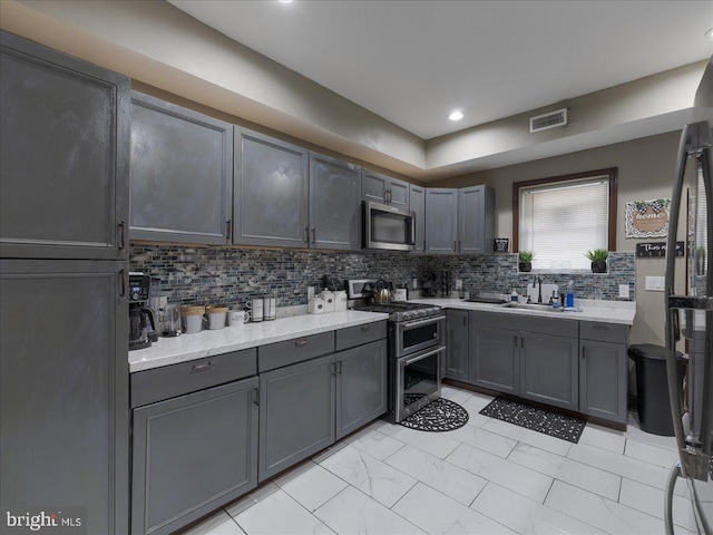 kitchen with stainless steel appliances, sink, decorative backsplash, and gray cabinets