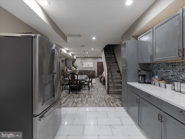 kitchen with gray cabinets, stainless steel refrigerator with ice dispenser, and backsplash