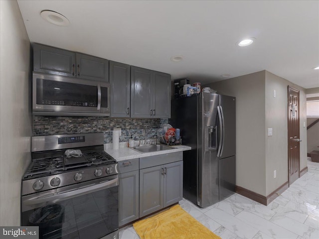 kitchen with tasteful backsplash, sink, gray cabinets, and appliances with stainless steel finishes