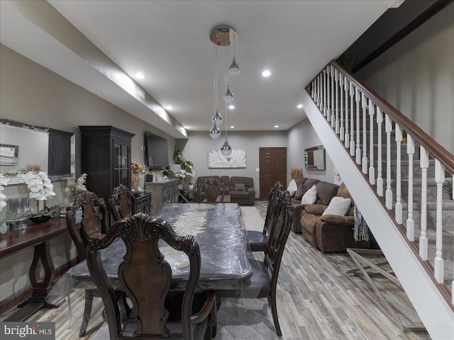 dining area with a wall mounted AC and light hardwood / wood-style floors