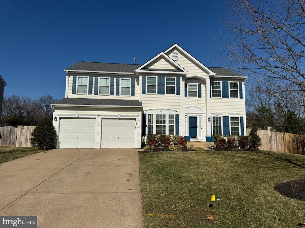 colonial house featuring a garage and a front lawn