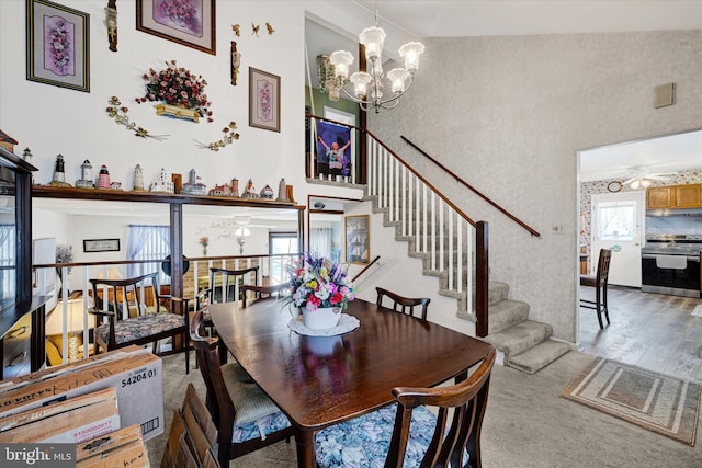 dining area featuring a high ceiling, wood-type flooring, and ceiling fan with notable chandelier