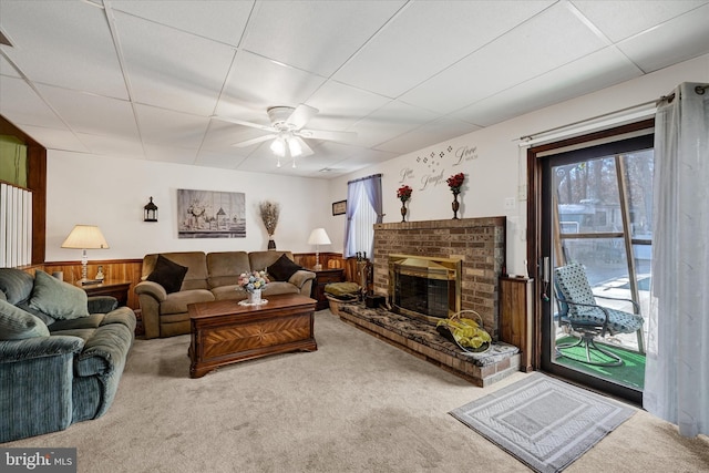 living room featuring ceiling fan, carpet, a paneled ceiling, and a fireplace