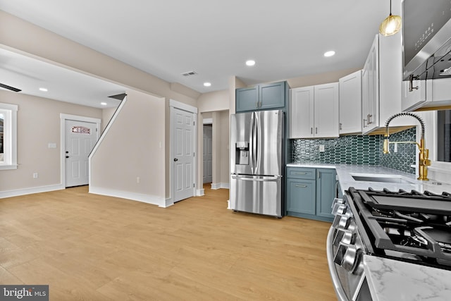 kitchen featuring sink, appliances with stainless steel finishes, backsplash, decorative light fixtures, and light wood-type flooring