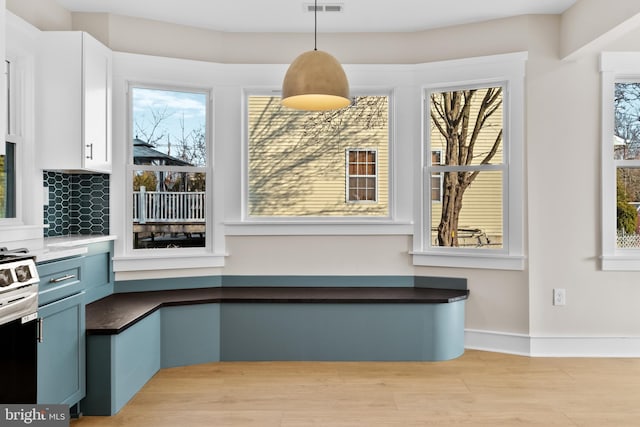 kitchen with pendant lighting, blue cabinetry, electric range, light hardwood / wood-style floors, and white cabinets