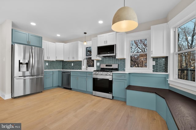 kitchen with blue cabinetry, stainless steel appliances, and decorative light fixtures