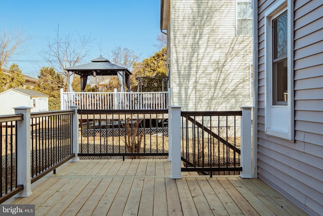 wooden terrace with a gazebo and a storage unit