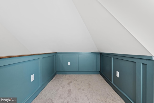 bonus room with lofted ceiling and light carpet