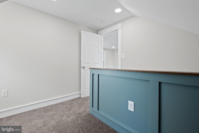 hall with vaulted ceiling and carpet flooring