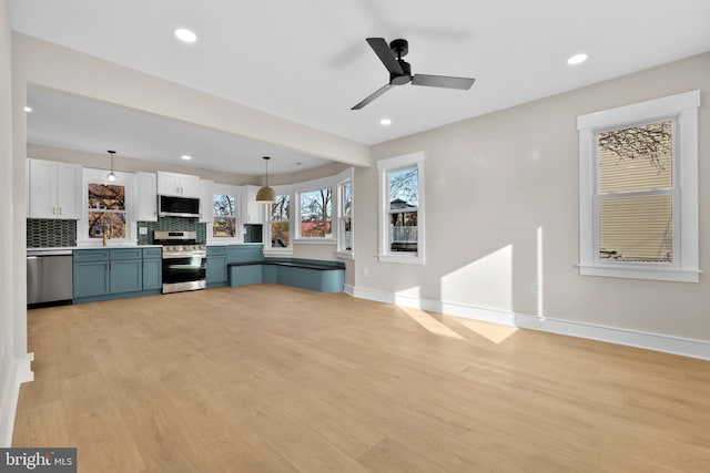 kitchen with pendant lighting, stainless steel appliances, light hardwood / wood-style floors, white cabinets, and decorative backsplash