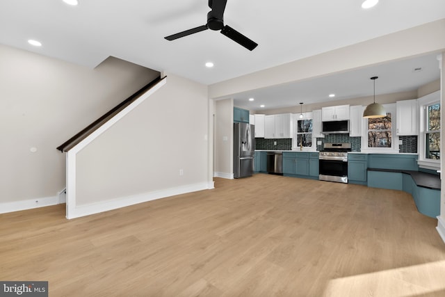 kitchen featuring blue cabinetry, white cabinetry, decorative light fixtures, stainless steel appliances, and backsplash