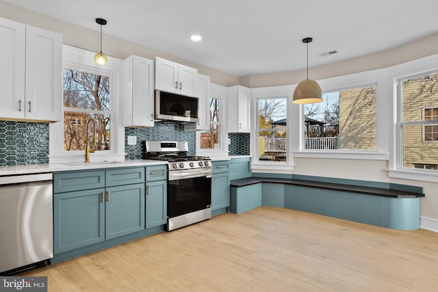 kitchen with hanging light fixtures, white cabinetry, appliances with stainless steel finishes, and sink