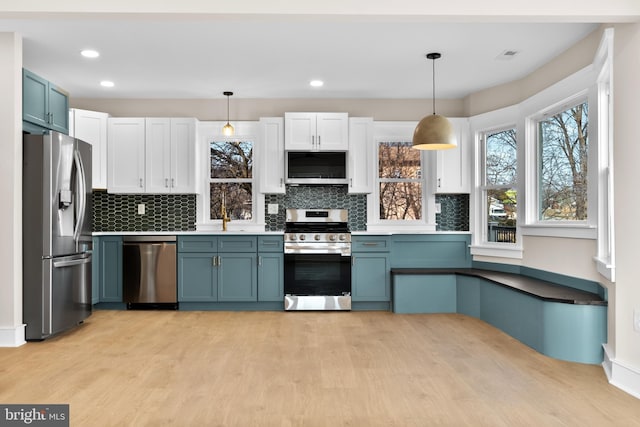 kitchen with blue cabinetry, appliances with stainless steel finishes, and decorative light fixtures