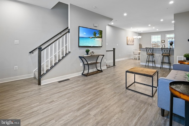 living area with recessed lighting, visible vents, light wood-style flooring, baseboards, and stairs