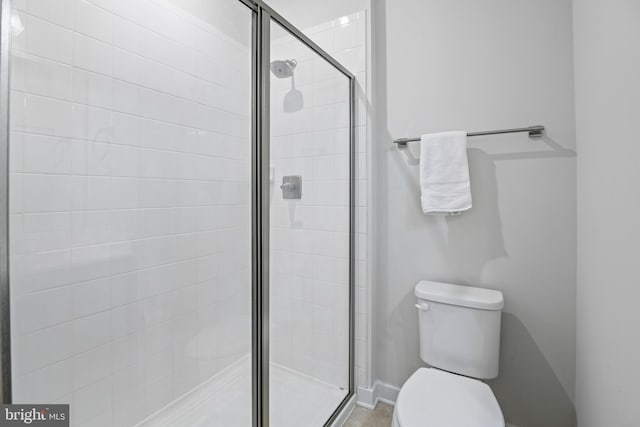 bathroom with a stall shower, baseboards, and toilet