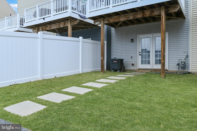 view of yard with fence, central AC unit, and a wooden deck