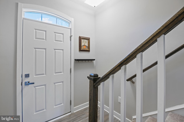 foyer entrance featuring baseboards, stairway, and wood finished floors