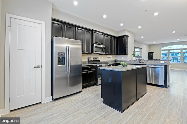 kitchen with a peninsula, appliances with stainless steel finishes, a kitchen island, and dark cabinets