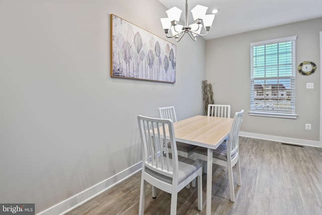 dining space with visible vents, a notable chandelier, baseboards, and wood finished floors